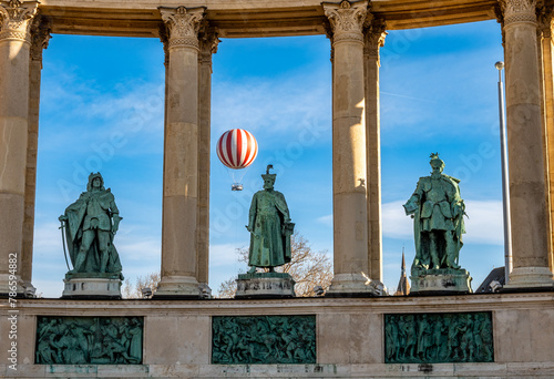 Red and white baloon with passengers rising high above Heroes Square and city park Varosliget in the city of Budapest, Hungary