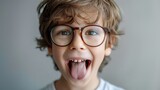 Playful young boy sticking out his tongue, wearing glasses. Ideal for educational and fun concepts