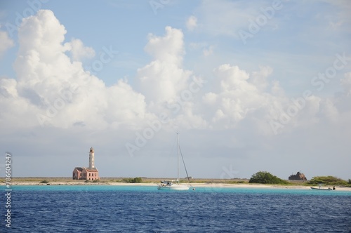 A small sailboat is floating in the ocean near a lighthouse remote loneliness cloudy photo