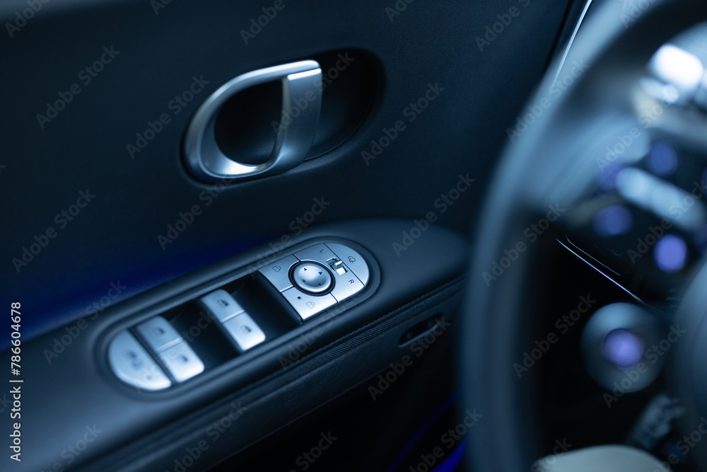 Window control buttons in modern luxury electric car. Car leather interior details of door handle with windows controls and adjustments. Car window controls. Door handle with power window control Window control buttons in modern luxury electric car. Car leather interior details of door handle with windows controls and adjustments. Car window controls. Door handle with power window control