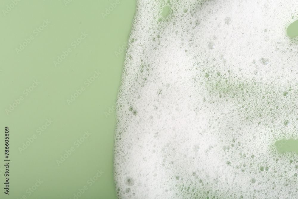 Naklejka premium White fluffy foam on green background, top view. Space for text