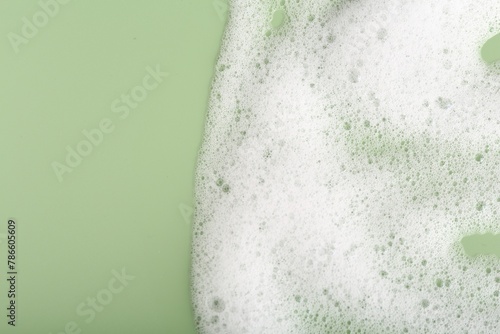 White fluffy foam on green background, top view. Space for text