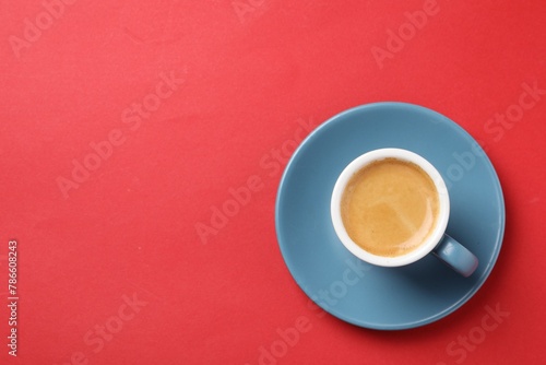 Aromatic coffee in cup on red background  top view. Space for text