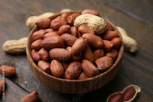 Fresh peanuts in bowl on wooden table, closeup