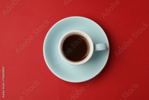 Tasty coffee in cup on red background, top view
