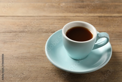Tasty coffee in cup on wooden table, closeup. Space for text