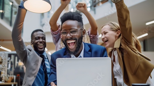With joyful smiles on their faces, the team of employees and entrepreneurs looks at the laptop, proud of the successful results of their joint work.