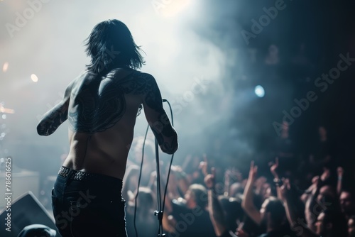 A rock frontman singing to the microphone to the crowd on a concert in a stage backlights. Back view photo