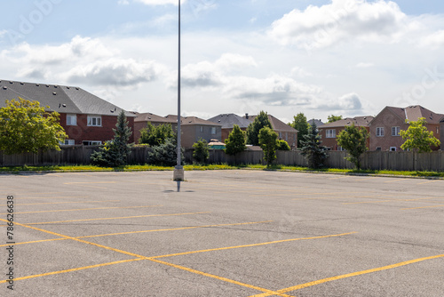 Photography Empty parking lot with lined spaces - lone light pole - suburban homes background - clear sky with clouds
