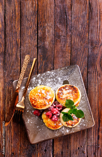 Cottage cheese pancakes with raspberries on wooden background, breakfast or lunch