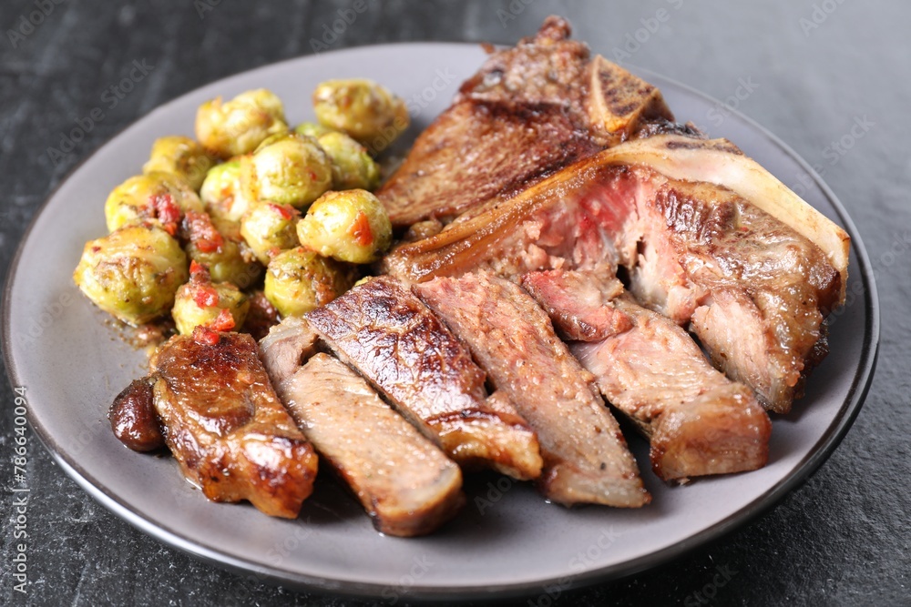 Delicious fried beef meat and vegetables on black table, closeup Delicious fried beef meat and vegetables on black table, closeup