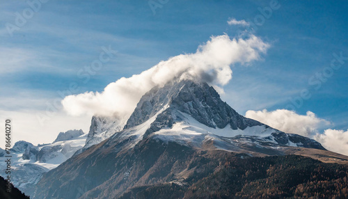 a very tall mountain with some clouds in the air and a lot of snow on the top of the mountain © Nicolas