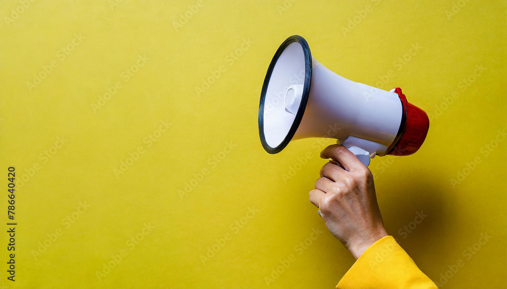 a woman's hand in yellow clothing holds a yellow megaphone on a yellow background. alarm a woman's hand in yellow clothing holds a yellow megaphone on a yellow background. alarm