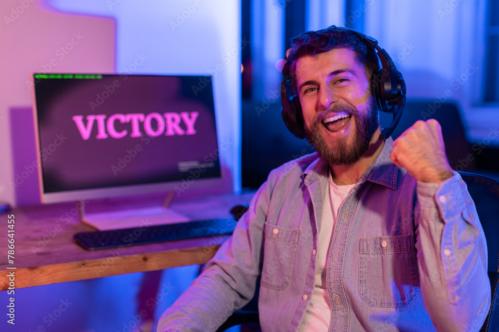 Gamer exuberantly fist pumps with 'VICTORY' on desktop screen Gamer exuberantly fist pumps with 'VICTORY' on desktop screen