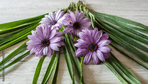 group of purple flowers sits atop a white table  surrounded by green stems