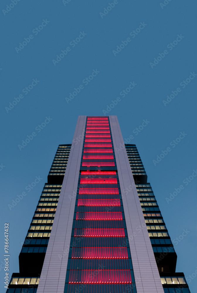 Naklejka premium Illuminated modern skyscraper against twilight sky
