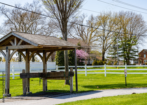 Rural Lancaster, scene with an Amish horse harness station, white fences, and a blooming pink tree, evoking peaceful countryside life. High quality photo. Lancaster, PA US