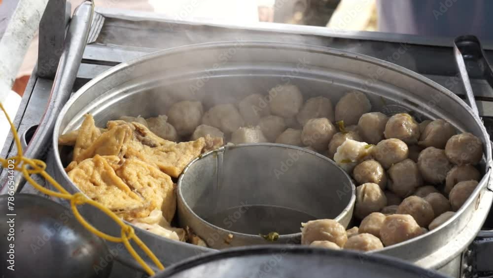 Bakso seller (meat ball seller) serves for customers in a stall cart. Bakso is one of indonesian street food Bakso seller (meat ball seller) serves for customers in a stall cart. Bakso is one of indonesian street food