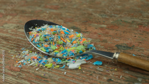 Microplastics in a spoon. A concept of consuming micro plastic particles, water and soil pollution. photo