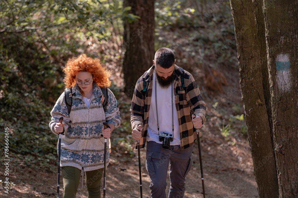 A beautiful and cheerful couple is hiking in the forest enjoying nature and each other's company A beautiful and cheerful couple is hiking in the forest enjoying nature and each other's company