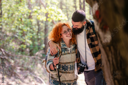 A beautiful and cheerful couple is hiking in the forest enjoying nature and each other's company