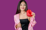 Beautiful young Asian woman with gift box for Valentine's Day on purple background