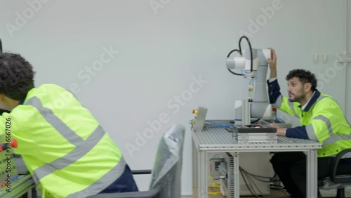 Group of multiethnic engineer researching and developing a robotics arm in scientific technology laboratory. Technician examining Industrial robot machine. Automated and manufacturing factory concepts
