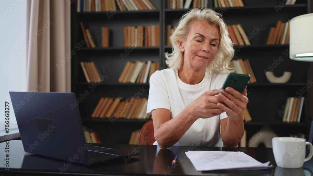 Confident stylish European middle aged senior woman using smartphone at workplace. Stylish older mature 60s lady businesswoman with cell phone in office. Boss leader using internet apps Confident stylish European middle aged senior woman using smartphone at workplace. Stylish older mature 60s lady businesswoman with cell phone in office. Boss leader using internet apps