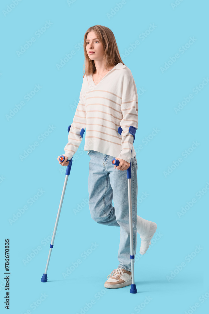 Injured young woman after accident with crutches on blue background Injured young woman after accident with crutches on blue background