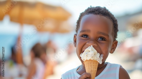 A smiling African American toddler boy child holds ice cream on a hot summer day on blurred beach. Ice cream in a waffle cone. A happy and contented child enjoy his sweet summer vacation  copy space.