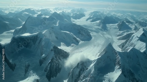 Breathtaking aerial view of a vast snow-covered mountain range under a clear sky, showcasing nature's grandeur.