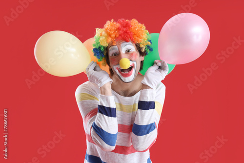 Portrait of clown with balloons on red background. April Fool's day celebration