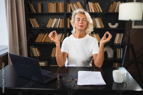 Yoga mindfulness meditation No stress keep calm. Middle aged woman practicing yoga at office. Woman taking break from work meditating relaxing. Mature lady doing breathing practice online yoga at work