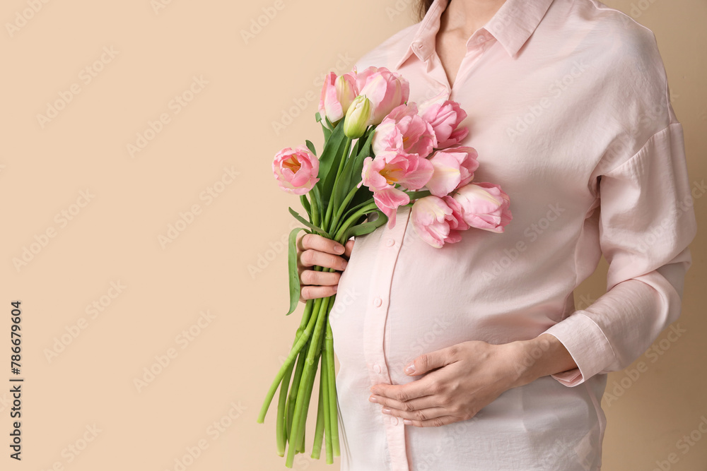 Young pregnant woman with tulips on beige background, closeup Young pregnant woman with tulips on beige background, closeup