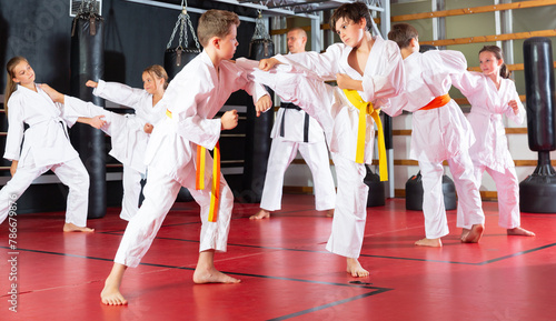 Adolescent boys and girls in kimono fighting with each other in gym.