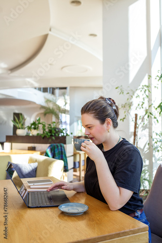 Casual Businesswoman Drinking Coffee and Using Laptop