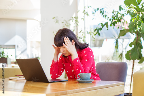 Stressed Businesswoman with Laptop at Sunny Workplace