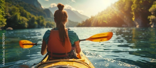 Solo female kayaking in serene stream in mountains, rear view, summer outdoor adventure concept