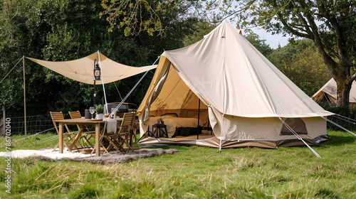 Luxurious glamping setup with a spacious bell tent, comfortable outdoor furniture, and warm lighting in a pastoral setting