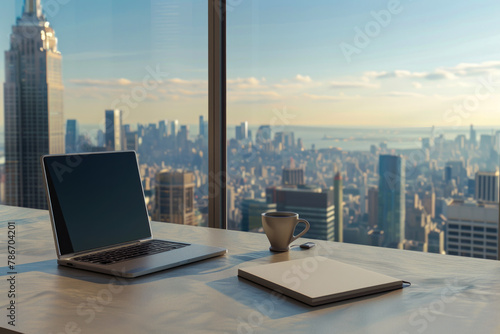 Front view of office desktop with open laptop and notebook with large glass windows in the background in high floor office, copy space text 