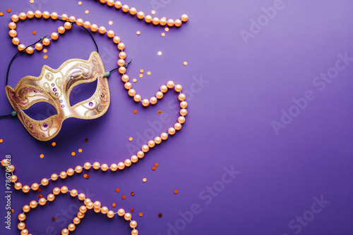 Mardi Gras carnival mask and beads on purple background