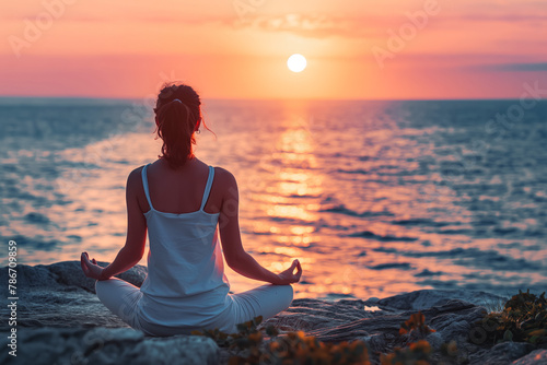 Young woman practice yoga and meditation near the sea at sunrise, healthy lifestyle concept, lotus position © VisualProduction