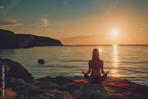 Young woman practice yoga and meditation near the sea at sunrise, healthy lifestyle concept, lotus position © VisualProduction