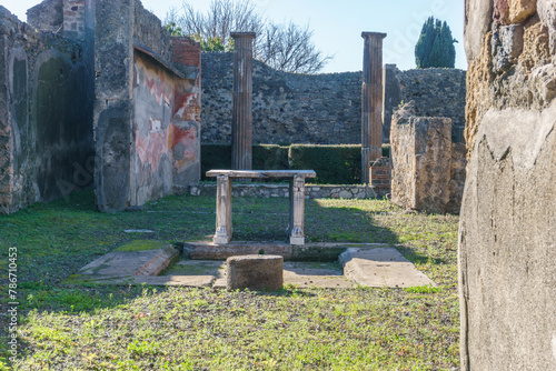 Table made out of stone surrounded by grass in ruins of ancient roman city of Pompeii, Campania, Italy