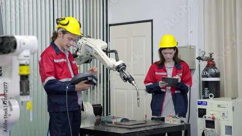 Group of multiethnic engineer researching and developing a robotics arm in scientific technology laboratory. Technician examining Industrial robot machine. Automated and manufacturing factory concepts