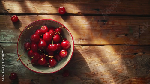 A bowl of bing cherries on a wooden tabletop or picnic table. photo