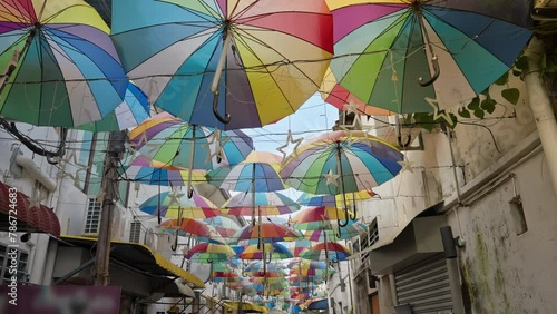 Colorful decoration umbrellas hang overhead above a walking pedestrian street in George Town, Penang, Malaysia