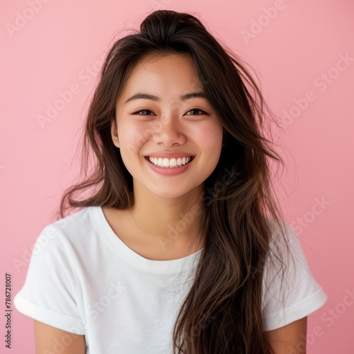 Bubbly Asian woman with curly hair and a bright smile, dressed in white, set against a playful pink backdrop, exuding charm and vivacity. © StockWorld