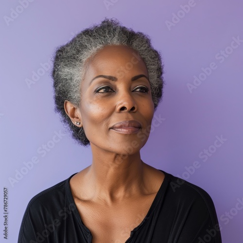 Confident middle-aged Black woman with elegant gray hair, in contemplation, against a subtle lavender background.