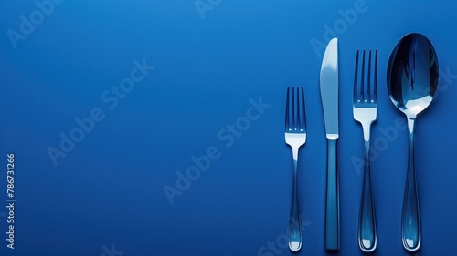 Silver cutlery set including knife, fork, spoon, and teaspoon on blue background